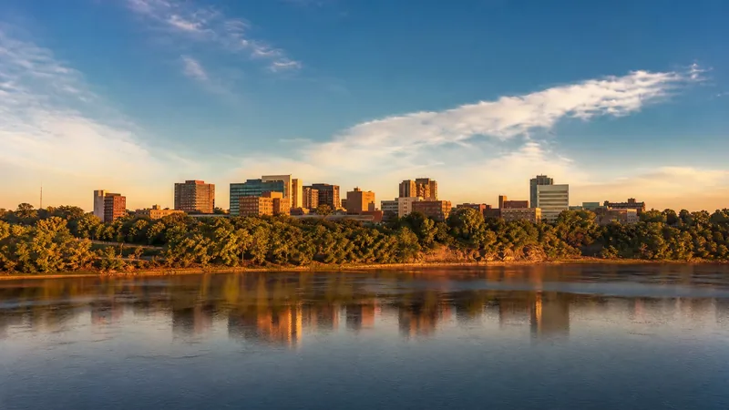 Missouri River capital city with a low skyline of mid-rise buildings above wooded river bluffs, morning light, Bismarck Business License